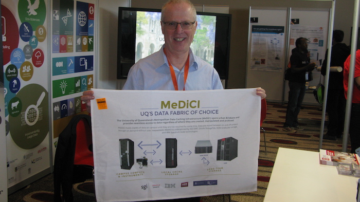 RCC Director Prof. David Abramson with the MeDiCI tea towel at the QCIF exhibition booth, which RCC was represented at, at  the eResearch Australasia Conference.
